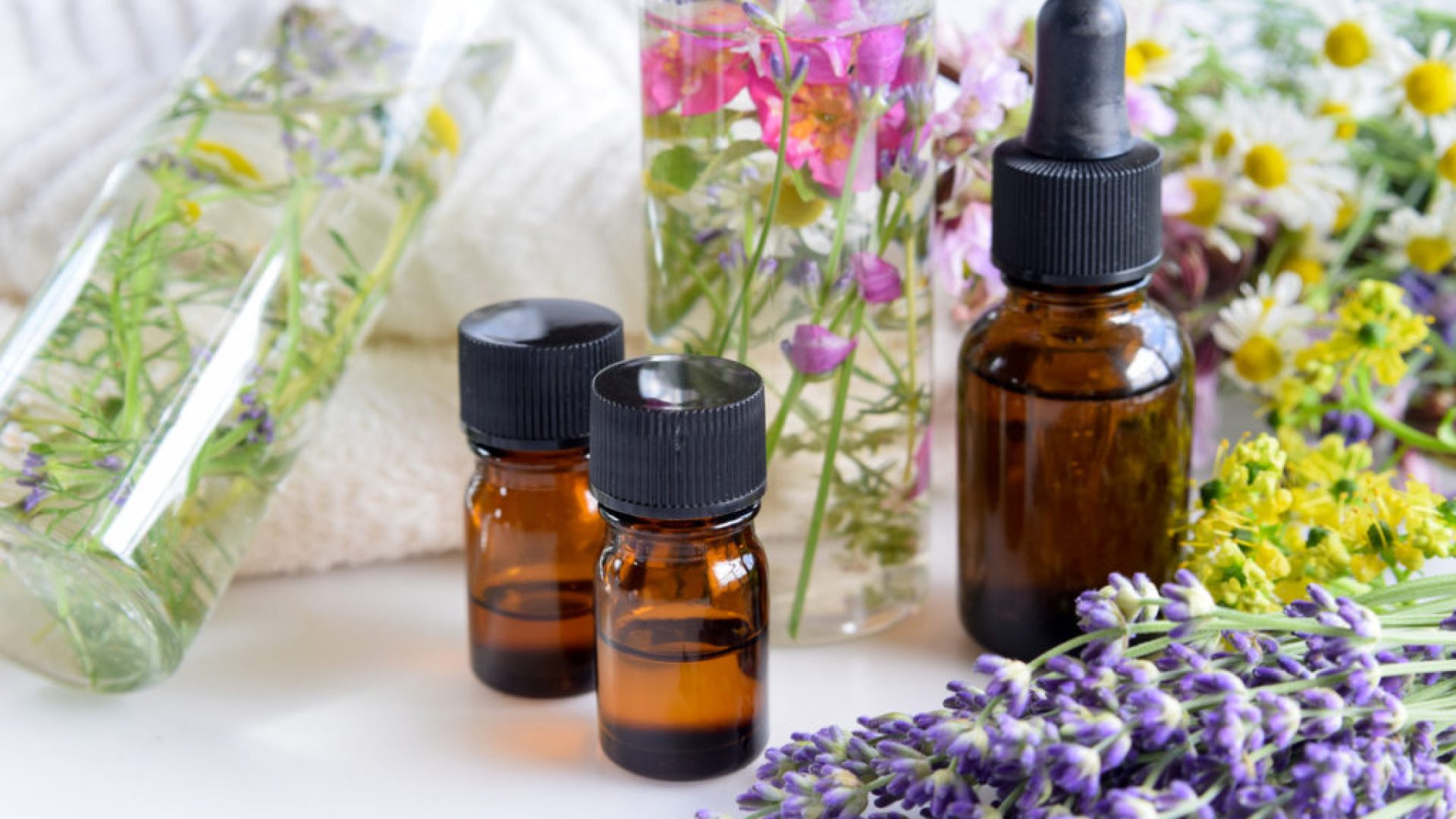 essential oils and natural cosmetics with fresh herbal leaves and flowers for beauty treatment